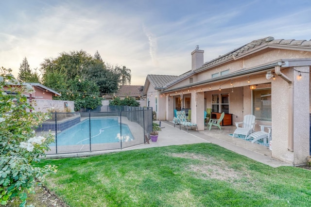 pool at dusk featuring a patio area and a yard