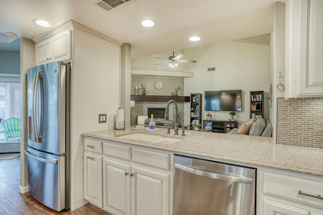 kitchen featuring white cabinets, appliances with stainless steel finishes, hardwood / wood-style flooring, and light stone countertops