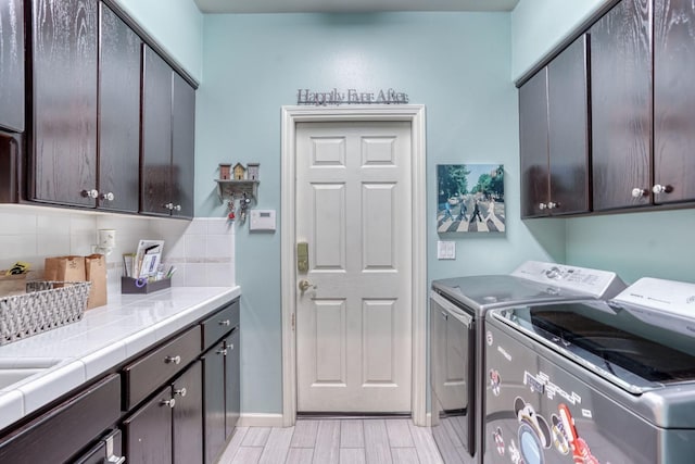 washroom with cabinets, light wood-type flooring, and independent washer and dryer