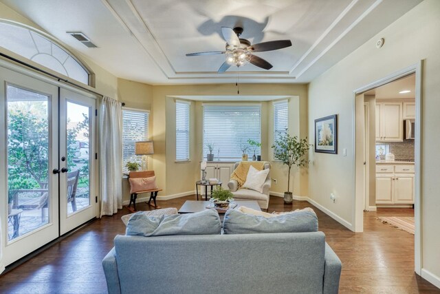 interior space with dark wood-type flooring, french doors, ceiling fan, and a raised ceiling