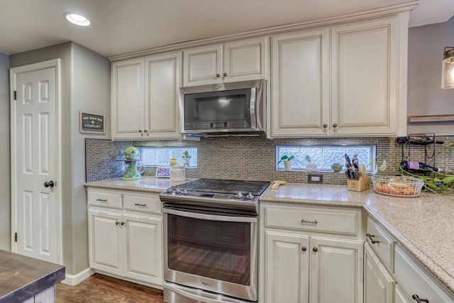 kitchen with dark wood-type flooring, decorative backsplash, appliances with stainless steel finishes, and cream cabinets