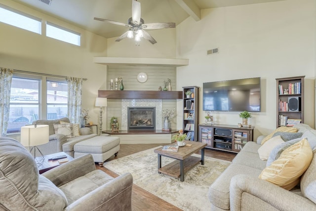 living room with high vaulted ceiling, light hardwood / wood-style flooring, ceiling fan, and beam ceiling