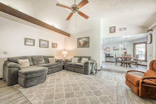 living area featuring lofted ceiling, a textured ceiling, visible vents, a ceiling fan, and light wood-type flooring