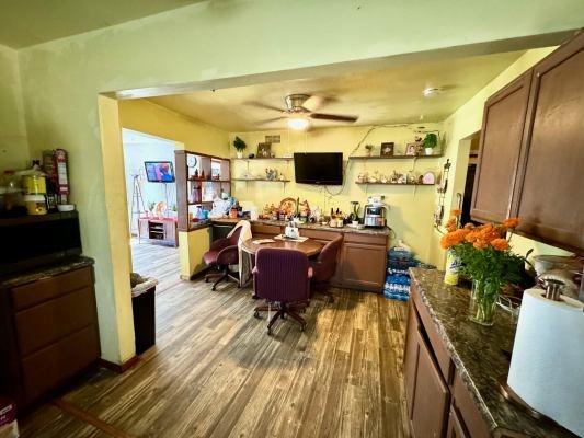 bar featuring dark stone countertops, ceiling fan, and dark hardwood / wood-style floors