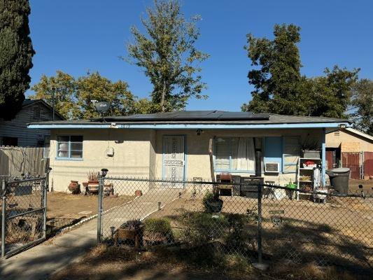 3819 E Belgravia Ave, Fresno, CA 93725 - view of front of property featuring roof mounted solar panels, covered porch, a fenced front yard, and stucco siding