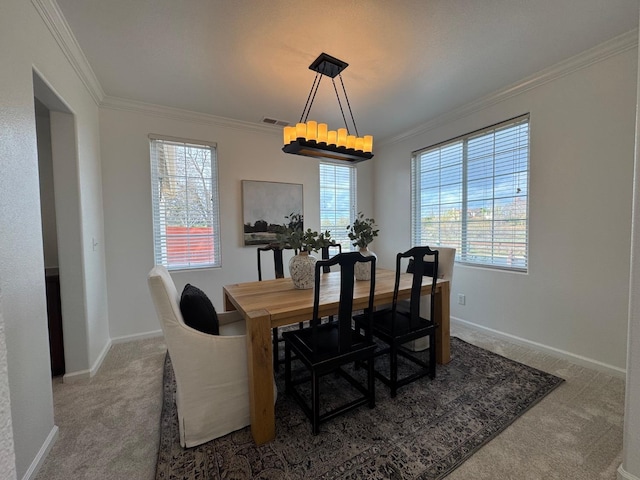 carpeted dining area featuring crown molding, plenty of natural light, and a chandelier