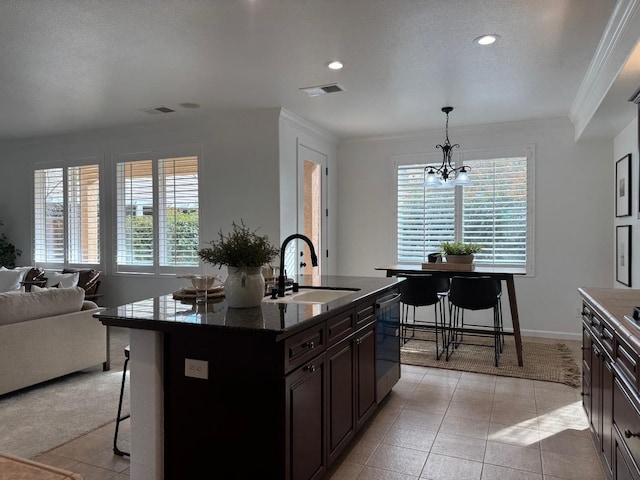 kitchen featuring sink, a breakfast bar area, stainless steel dishwasher, pendant lighting, and a kitchen island with sink