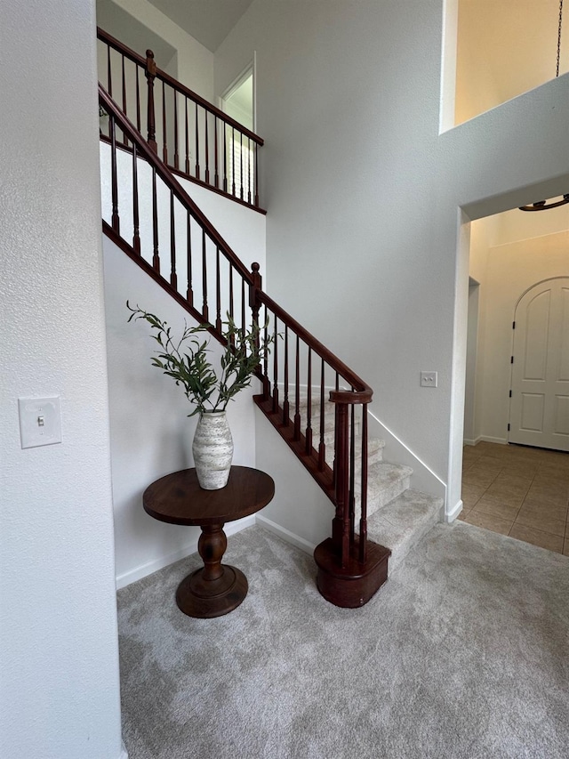 stairway with carpet and a high ceiling