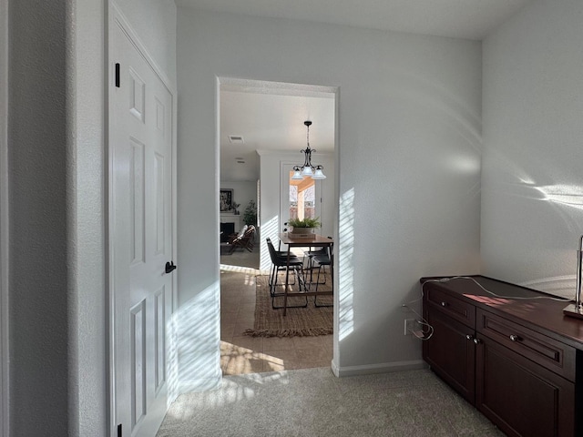 corridor featuring a chandelier and light carpet