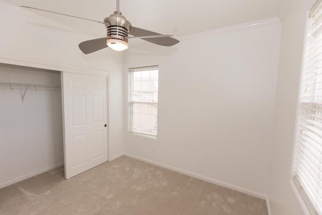 unfurnished bedroom featuring ornamental molding, light carpet, ceiling fan, and a closet