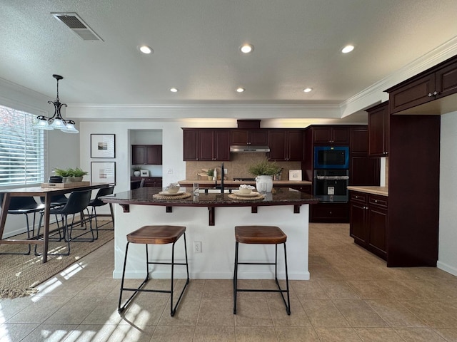 kitchen featuring built in microwave, a center island with sink, black oven, and dark brown cabinetry