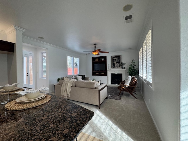 carpeted living room with crown molding and ceiling fan