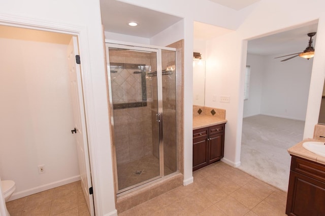 bathroom with a shower with door, ceiling fan, vanity, tile patterned floors, and toilet