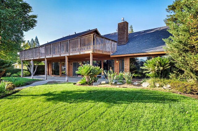 rear view of property featuring a patio area, a yard, and a wooden deck