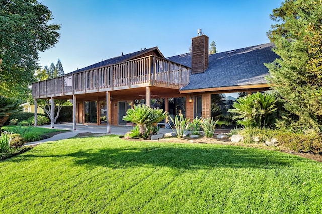 rear view of property featuring a patio, a lawn, a chimney, and a wooden deck