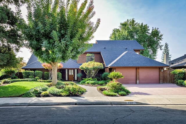 view of front of property with a garage, roof with shingles, driveway, and fence