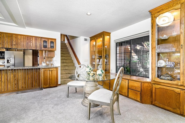 dining space with visible vents, light colored carpet, stairs, and a textured ceiling