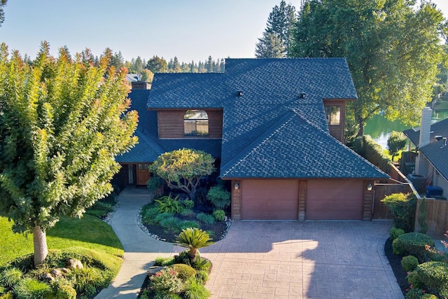 view of front of home with decorative driveway, an attached garage, and a shingled roof