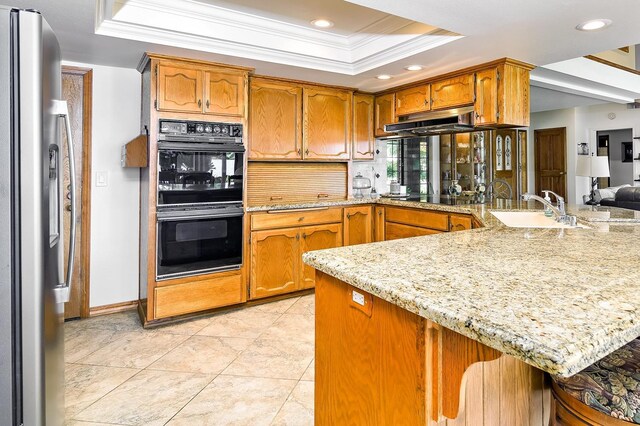 kitchen with kitchen peninsula, a tray ceiling, black appliances, and sink