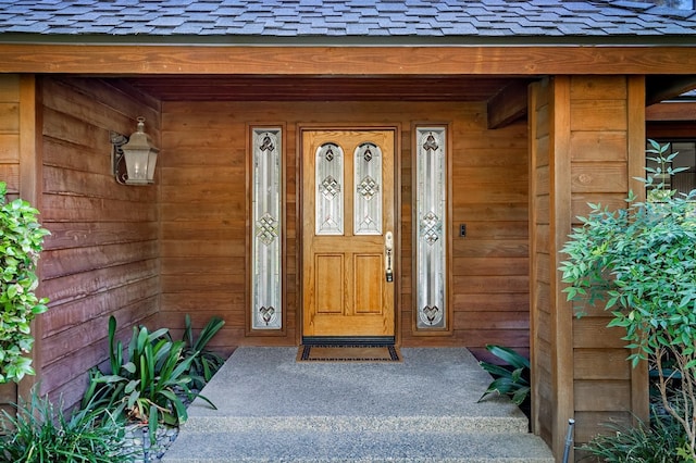 doorway to property with covered porch and roof with shingles