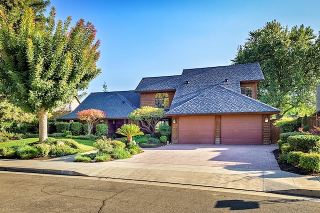 view of front of house with driveway, a shingled roof, and a garage