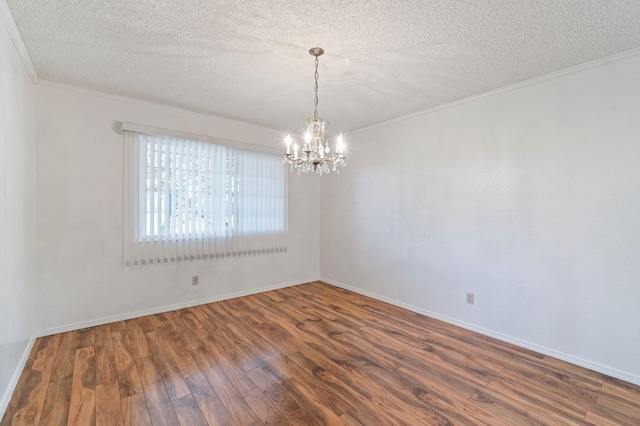 empty room with a chandelier, dark wood-type flooring, a textured ceiling, and ornamental molding