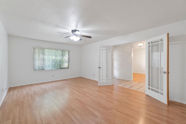 unfurnished room featuring ceiling fan, a textured ceiling, light hardwood / wood-style flooring, and french doors