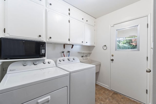 clothes washing area featuring cabinets and washer and dryer