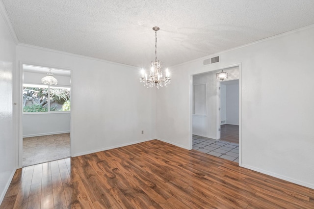 empty room featuring a textured ceiling, dark hardwood / wood-style floors, ornamental molding, and a notable chandelier