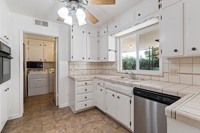 kitchen featuring separate washer and dryer, white cabinets, dishwasher, oven, and tile countertops