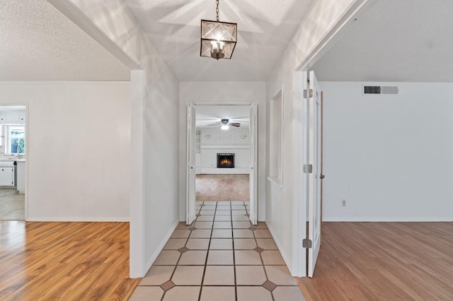 hall featuring light tile patterned flooring, an inviting chandelier, and a textured ceiling