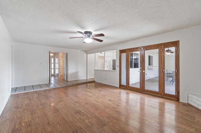 unfurnished living room featuring ceiling fan, a textured ceiling, french doors, and light wood-type flooring