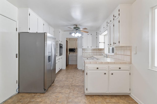 kitchen featuring sink, white cabinets, stainless steel fridge with ice dispenser, decorative backsplash, and tile counters