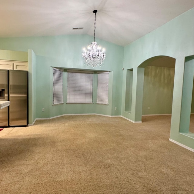 unfurnished dining area with a chandelier, vaulted ceiling, and light colored carpet