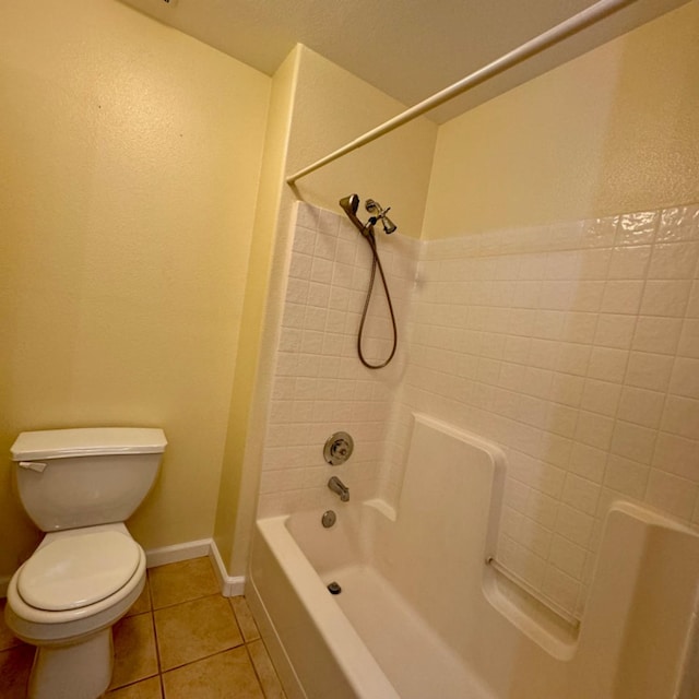 bathroom featuring tile patterned flooring, tiled shower / bath combo, and toilet