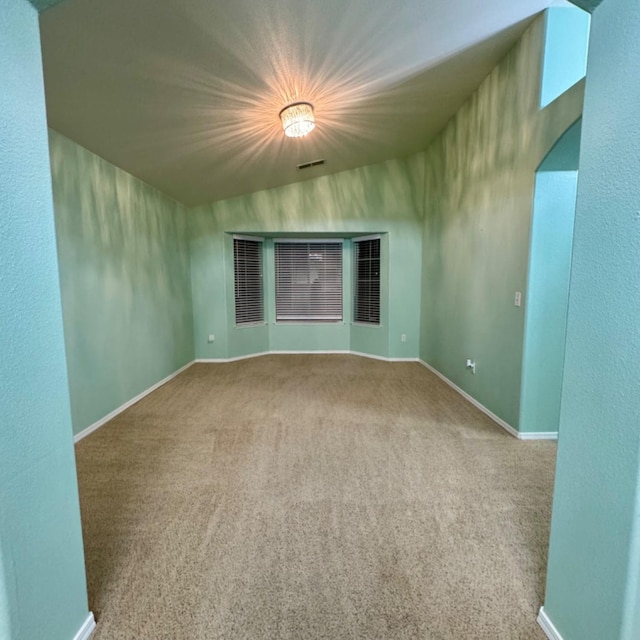 carpeted empty room featuring lofted ceiling