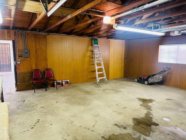 basement featuring electric panel and wood walls