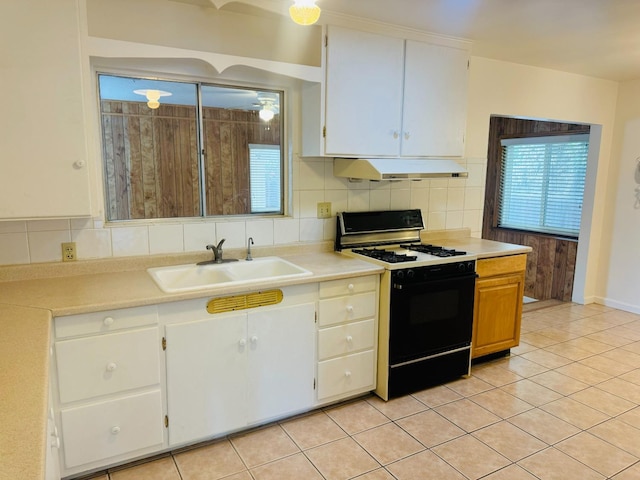 kitchen featuring tasteful backsplash, light tile patterned floors, black range with gas stovetop, sink, and white cabinets