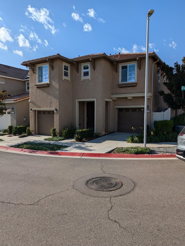 view of front of house featuring an attached garage, fence, driveway, and stucco siding