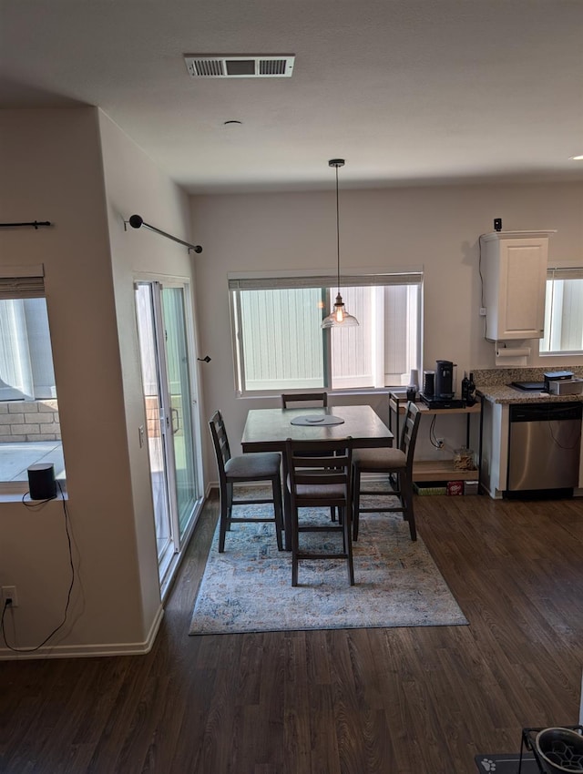 dining room with dark wood-type flooring and a healthy amount of sunlight