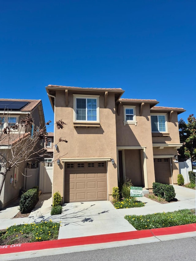 view of front of house featuring stucco siding, concrete driveway, and an attached garage