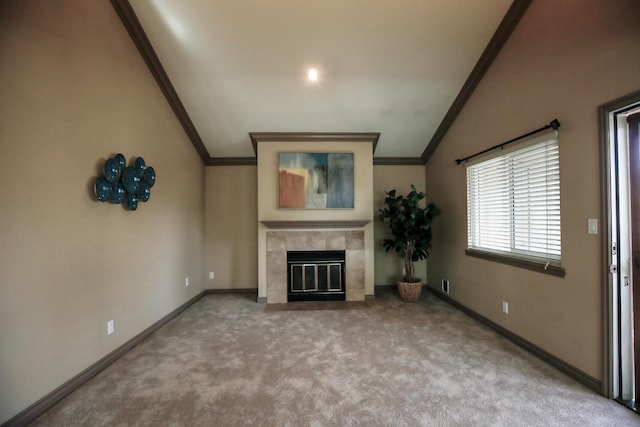 unfurnished living room with ornamental molding, carpet, a tile fireplace, and vaulted ceiling