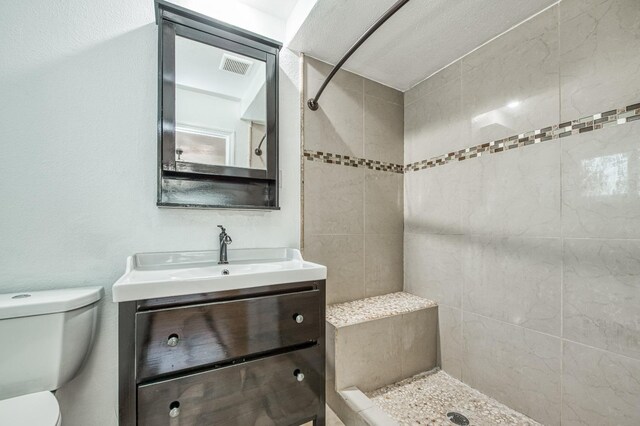 bathroom featuring vanity, toilet, and tiled shower