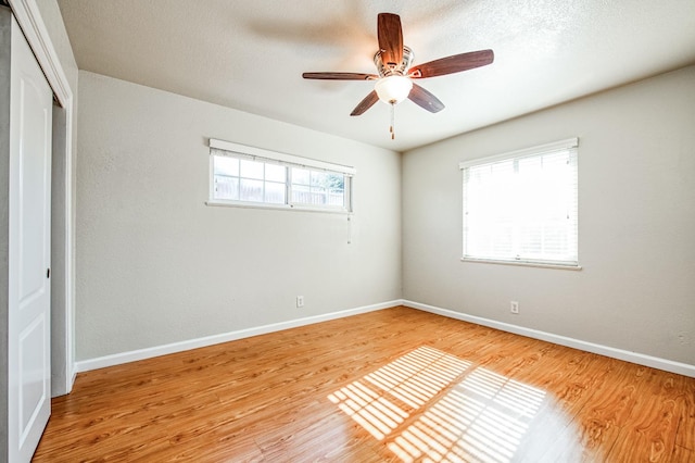 unfurnished bedroom with ceiling fan, multiple windows, and light wood-type flooring