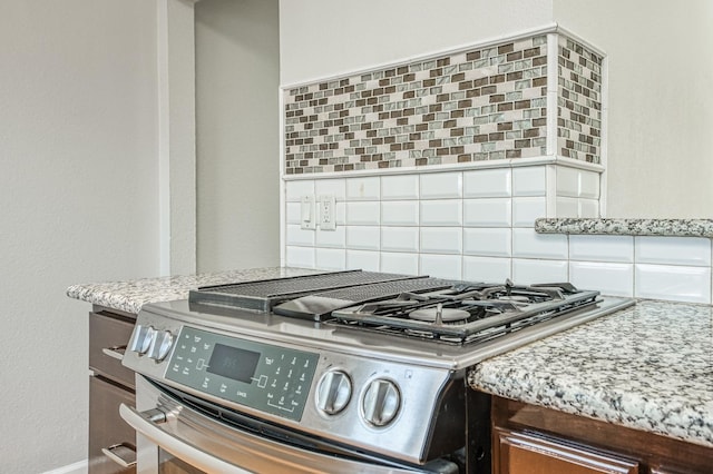 interior details with light stone countertops, stainless steel stove, and decorative backsplash