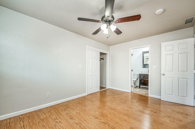 unfurnished bedroom with ensuite bathroom, light wood-type flooring, and ceiling fan