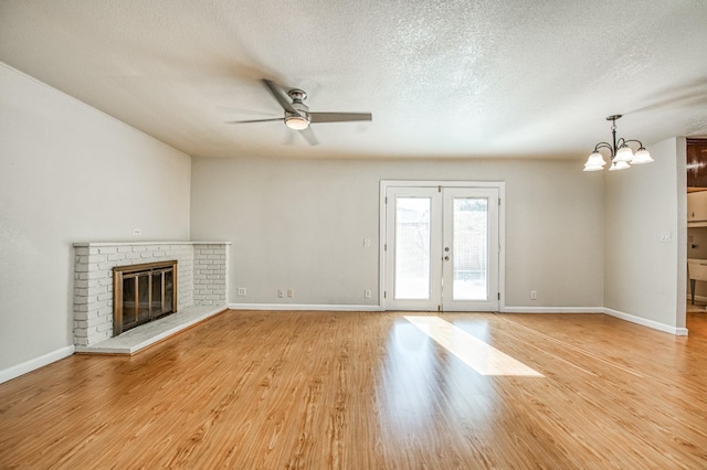 unfurnished living room with a textured ceiling, a brick fireplace, and light hardwood / wood-style flooring