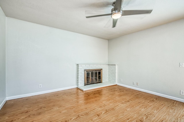 unfurnished living room with a brick fireplace, hardwood / wood-style flooring, and ceiling fan