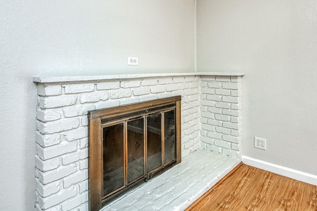 interior details with wood-type flooring and a brick fireplace