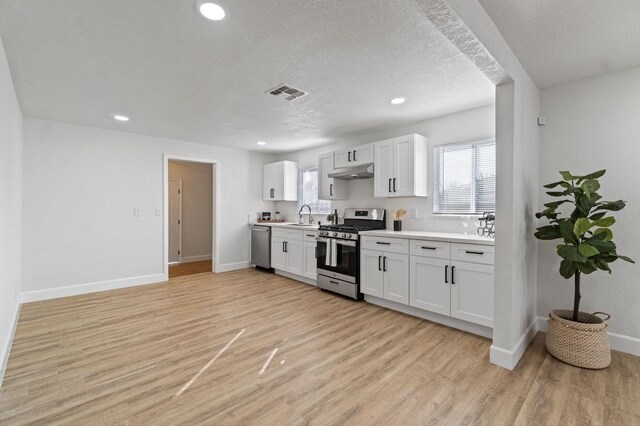 kitchen with light wood-style flooring, under cabinet range hood, stainless steel appliances, white cabinetry, and light countertops